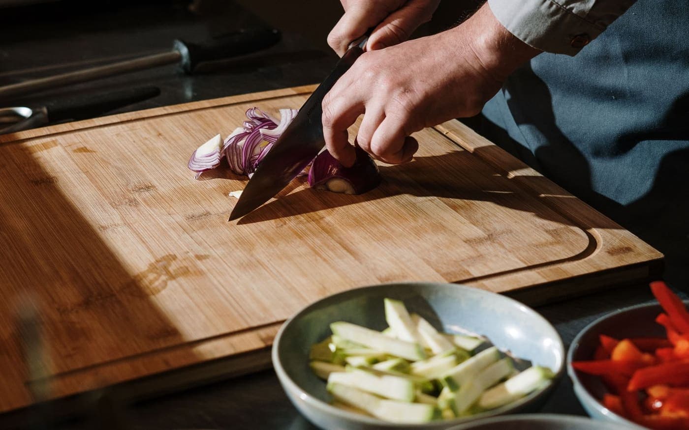 Mãos de um cozinheiro cortando legumes em uma cozinha profissional