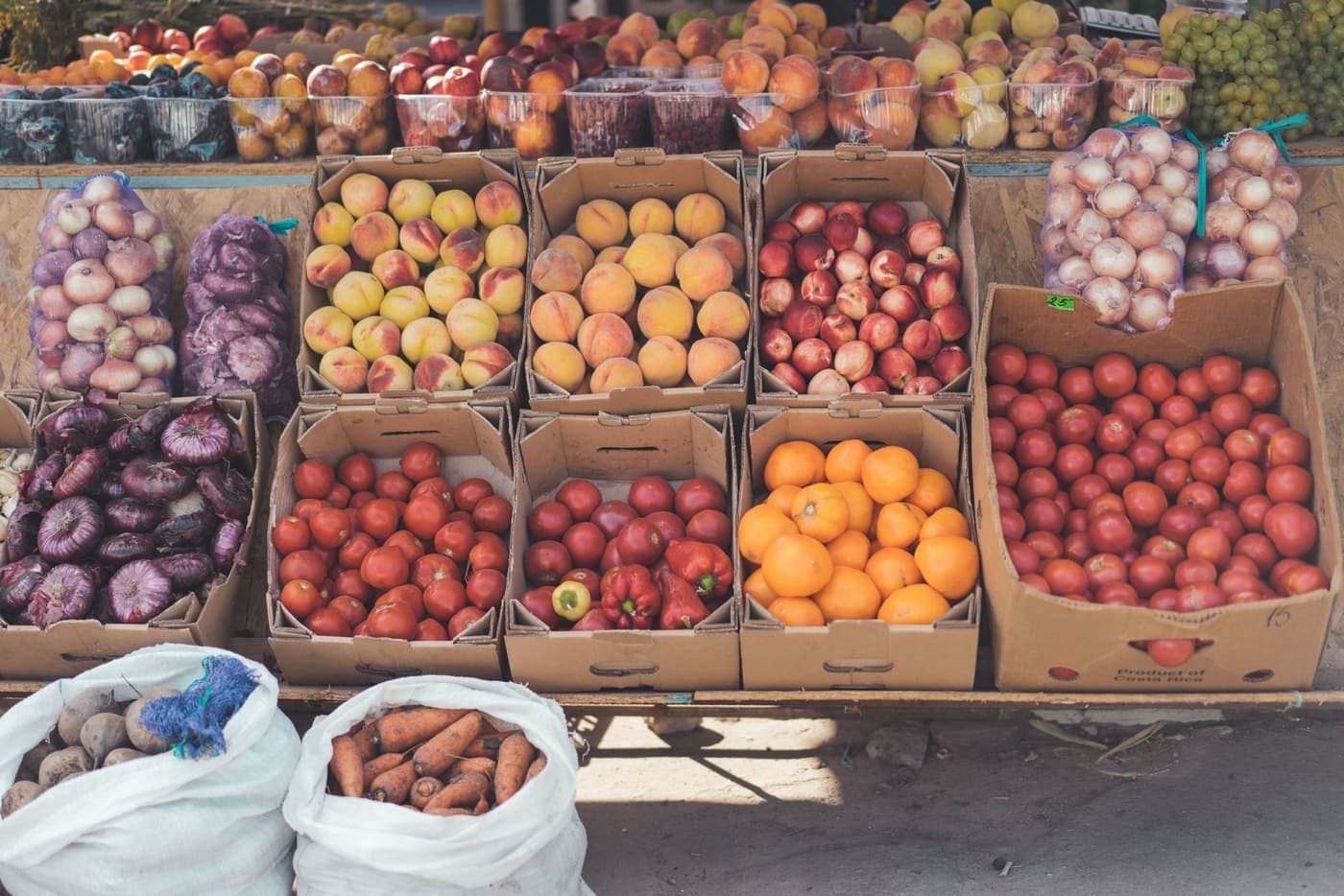 Caixas de frutas e legumes empilhadas, prontas para venda